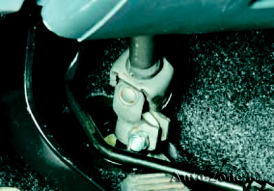 В салоне автомобиля под панелью приборов отверните гайку и извлеките стяжной болт крепления карданного шарнира промежуточного вала рулевой колонки к валу-шестерне рулевого механизма