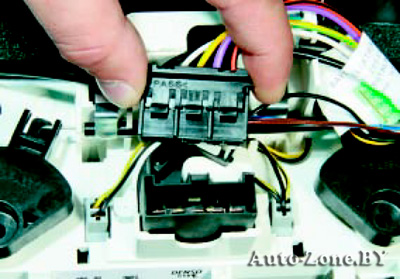 Нажмите на фиксатор колодки жгута проводов и отсоедините колодку от блока управления системой отопления (кондиционирования) и вентиляции
